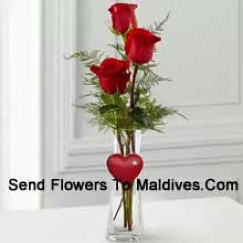 3 Red Roses In A Glass Vase Having A Small Heart Attached To It